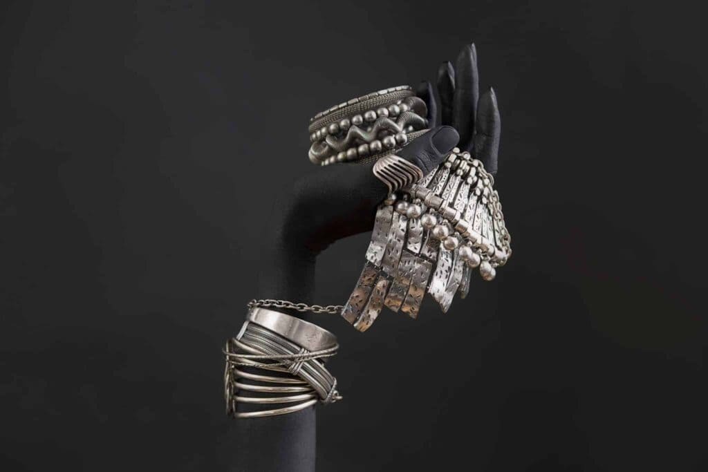 Silver jewelry collection featuring rings, bracelets, and earrings on a black background.