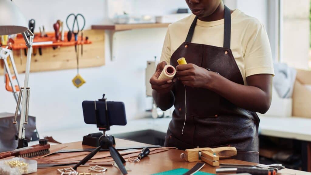 Black woman crafting jewelry in a workshop for small Black-owned businesses.