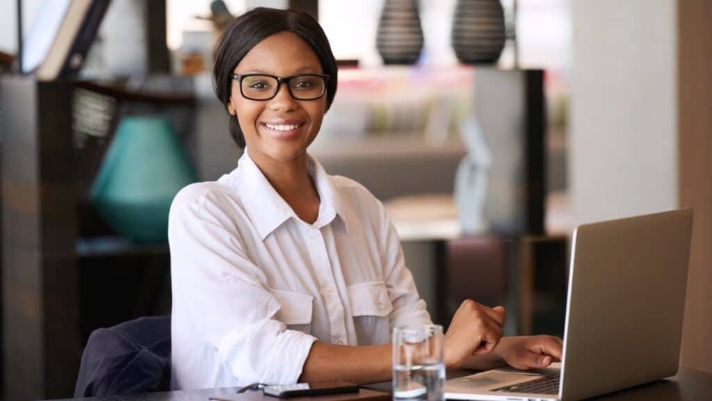 Efficient Black woman working on a laptop for marketplace sales tax compliance.