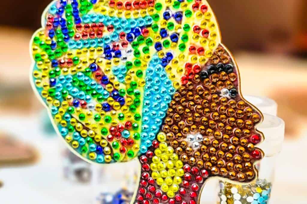 Brightly colored beaded art piece of a woman's profile with multicolored beads and intricate design.