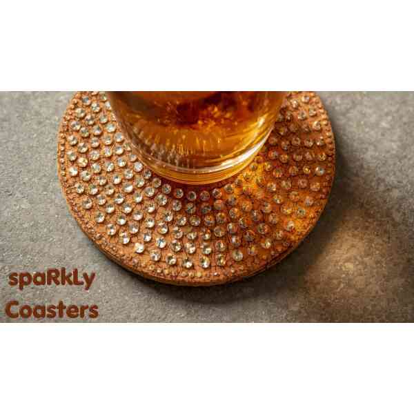 A sparkling coaster with rhinestones holding a glass of beverage on a textured surface.
