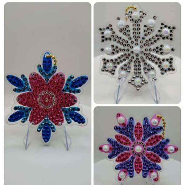 Pink and blue beaded snowflake ornaments with gold accents, displayed on clear stands.