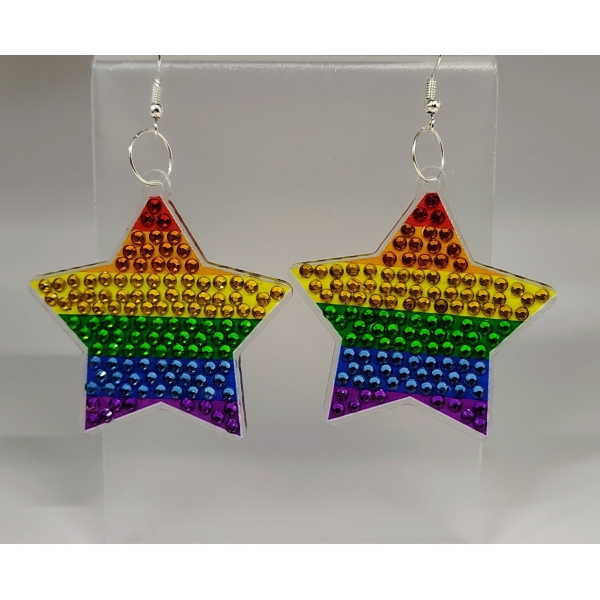 Rainbow star-shaped earrings with colorful rhinestones on a clear display stand.
