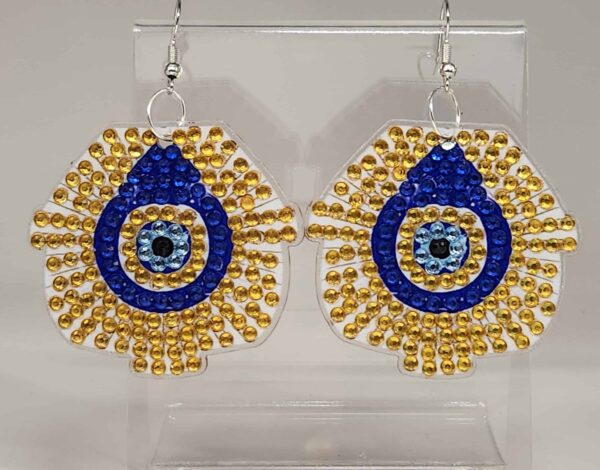 Colorful beaded earrings with blue, gold, and black accents, displayed on a clear stand.