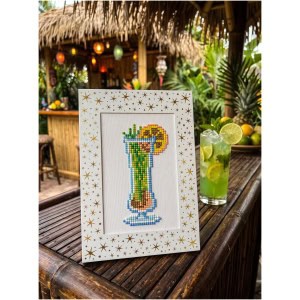 Colorful cross-stitch of a tropical cocktail on a wooden table.
